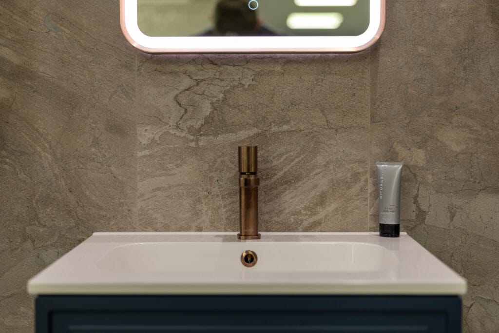 Bespoke sink - Blue vanity unit with a copper tap and large mirror with ambient lighting.