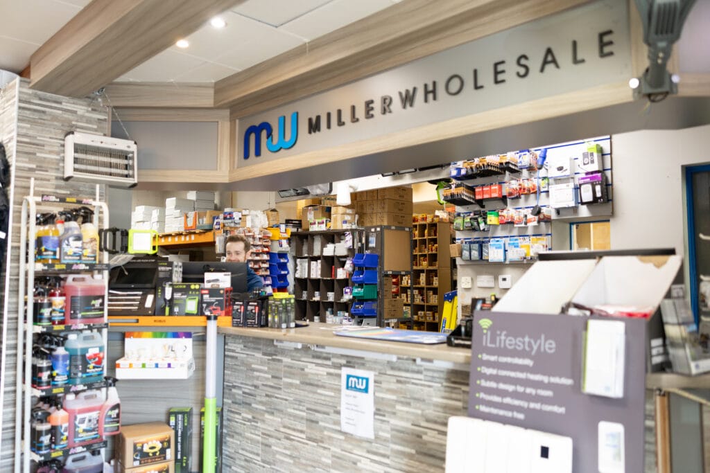 Miller Wholesale trade counter with electrical accessories, heating controls and parts bins behind the counter and a staff member at the till