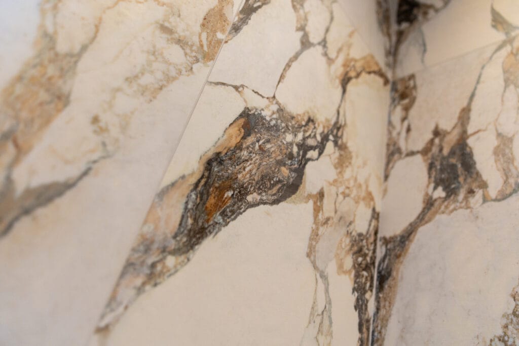 Large-format marble-effect porcelain wall tiles with gold and brown veining