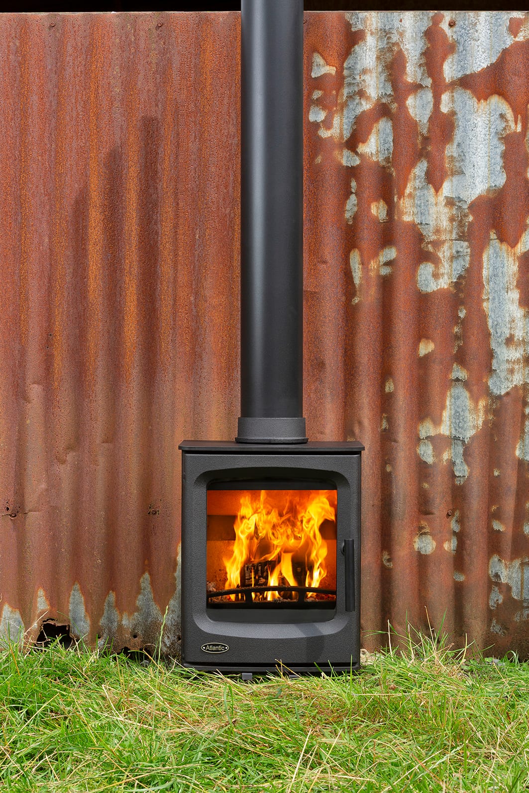 Atlantic Pearl 4 wood burning stove lit, photographed outdoors on stone
